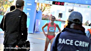 Athlete prepares for pole vault on a track with others watching.