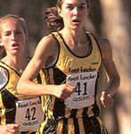 Athlete prepares for pole vault on a track with others watching.