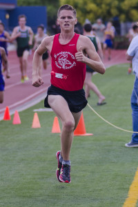 Athlete prepares for pole vault on a track with others watching.