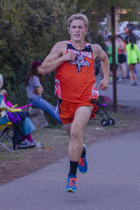 Athlete prepares for pole vault on a track with others watching.