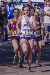 Athlete prepares for pole vault on a track with others watching.