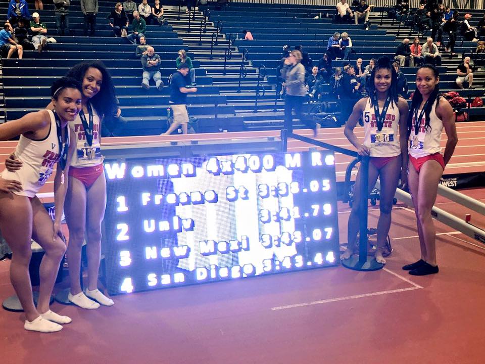 Athlete prepares for pole vault on a track with others watching.