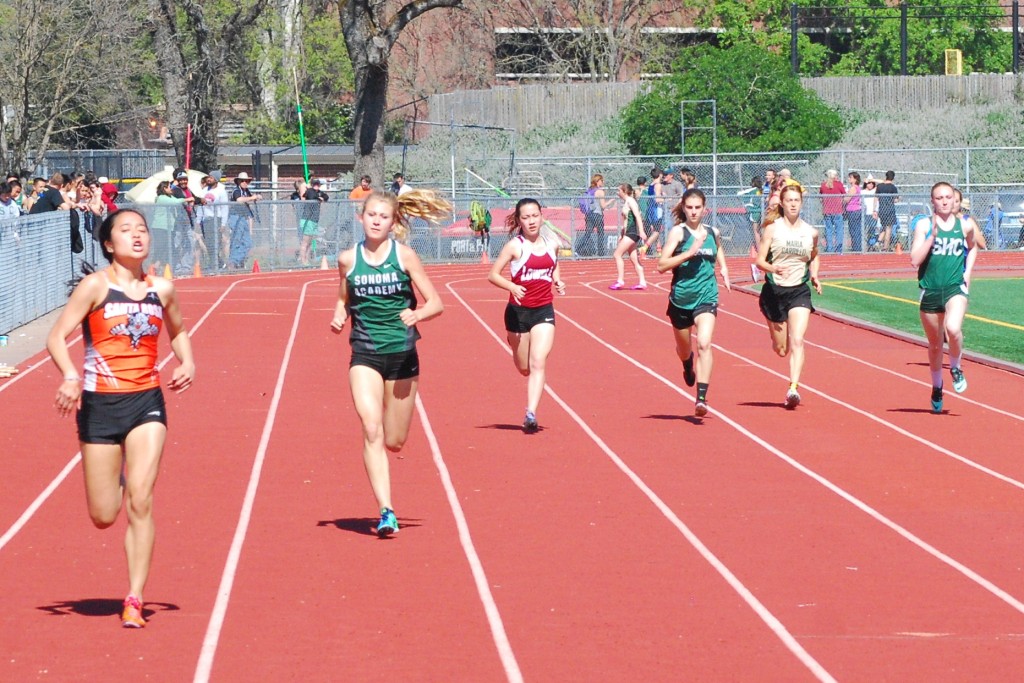 Athlete prepares for pole vault on a track with others watching.