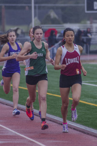 Athlete prepares for pole vault on a track with others watching.