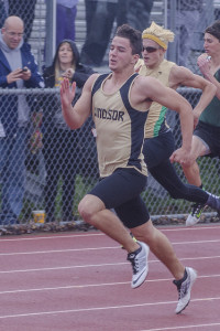 Athlete prepares for pole vault on a track with others watching.
