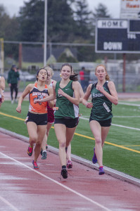 Athlete prepares for pole vault on a track with others watching.