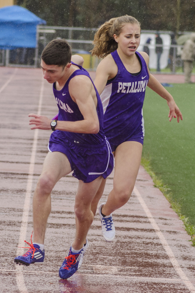 Athlete prepares for pole vault on a track with others watching.