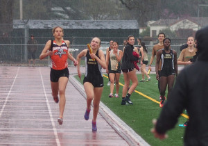Athlete prepares for pole vault on a track with others watching.