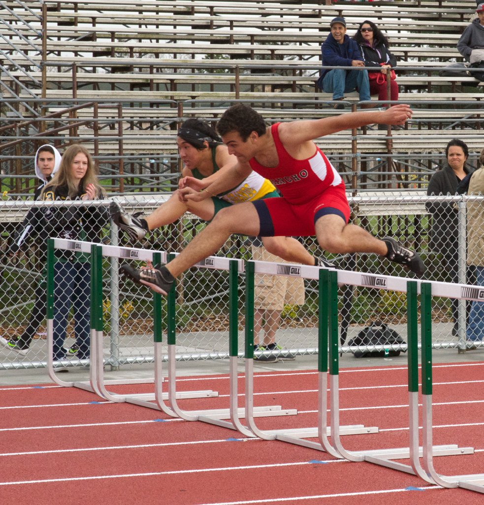Athlete prepares for pole vault on a track with others watching.