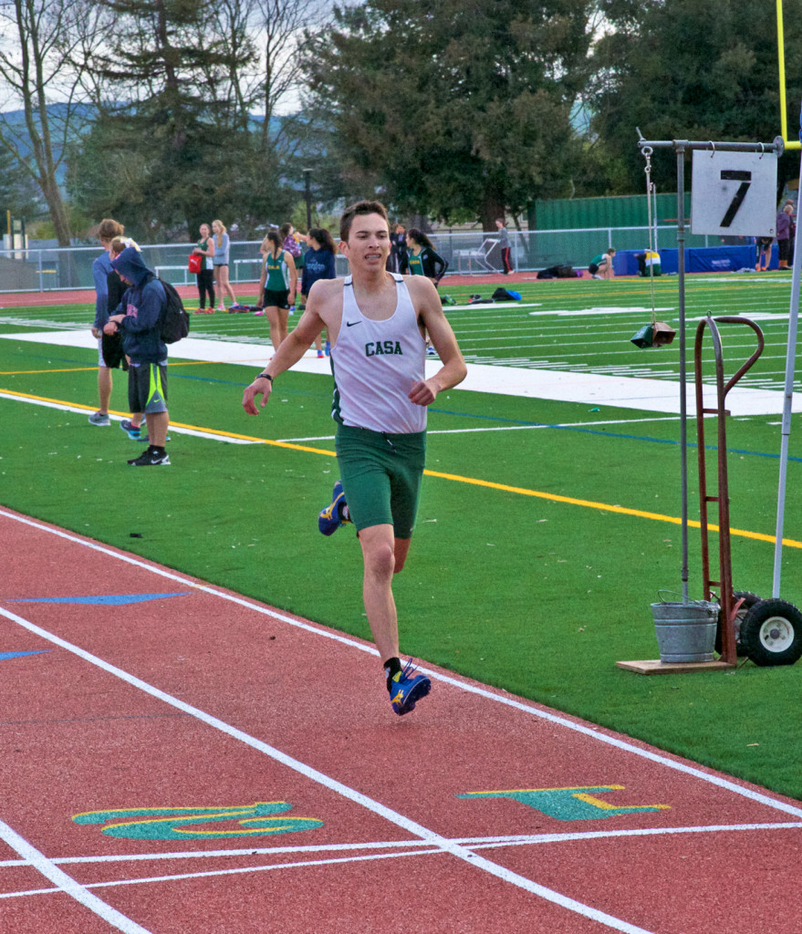 Athlete prepares for pole vault on a track with others watching.