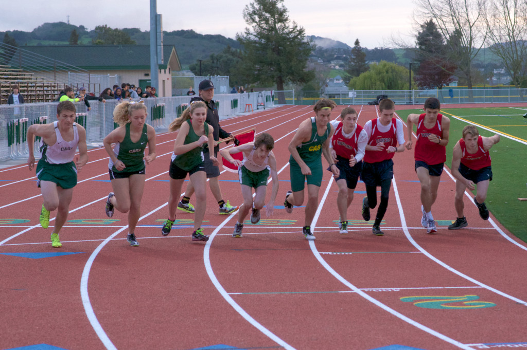 Athlete prepares for pole vault on a track with others watching.