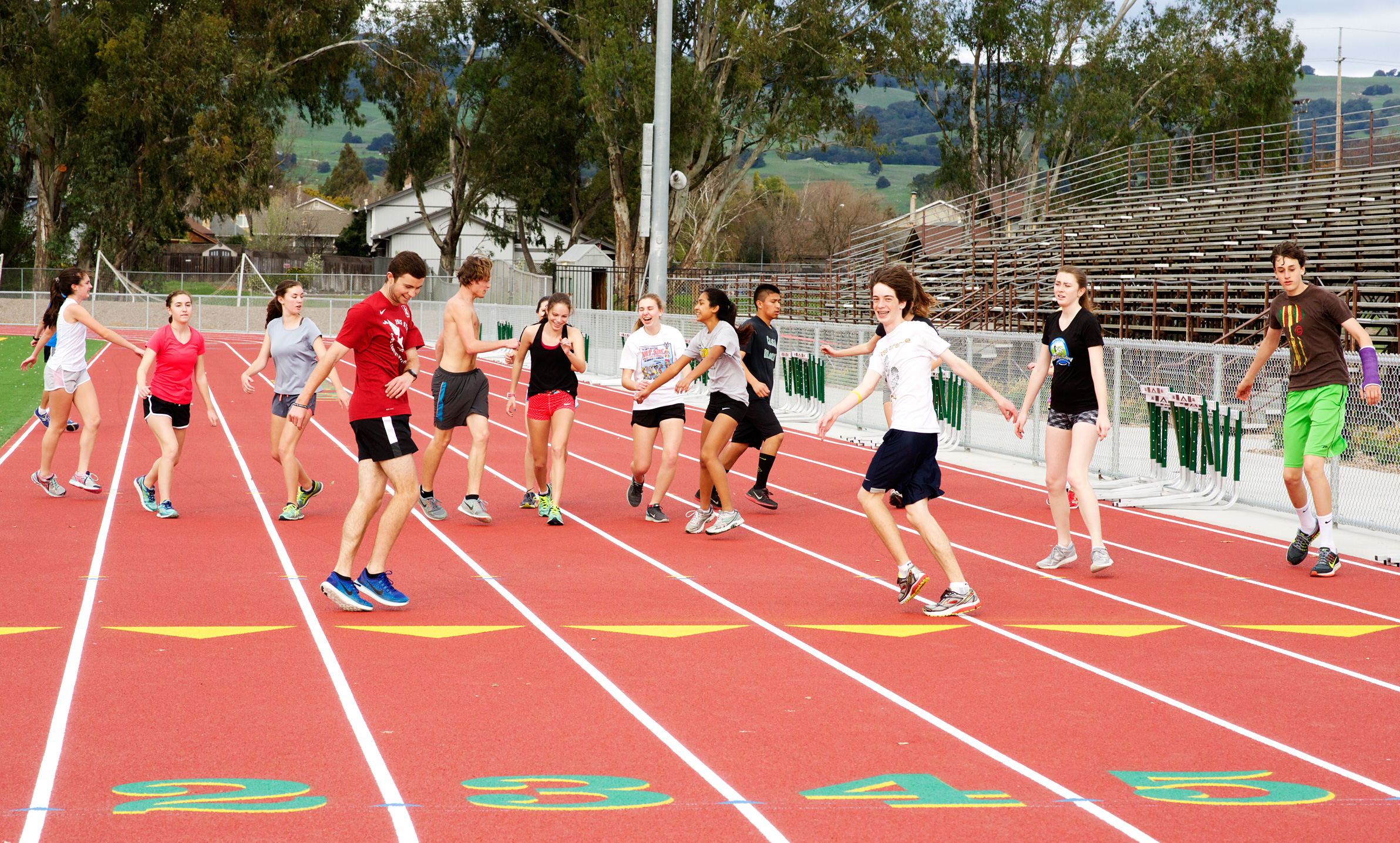 Athlete prepares for pole vault on a track with others watching.