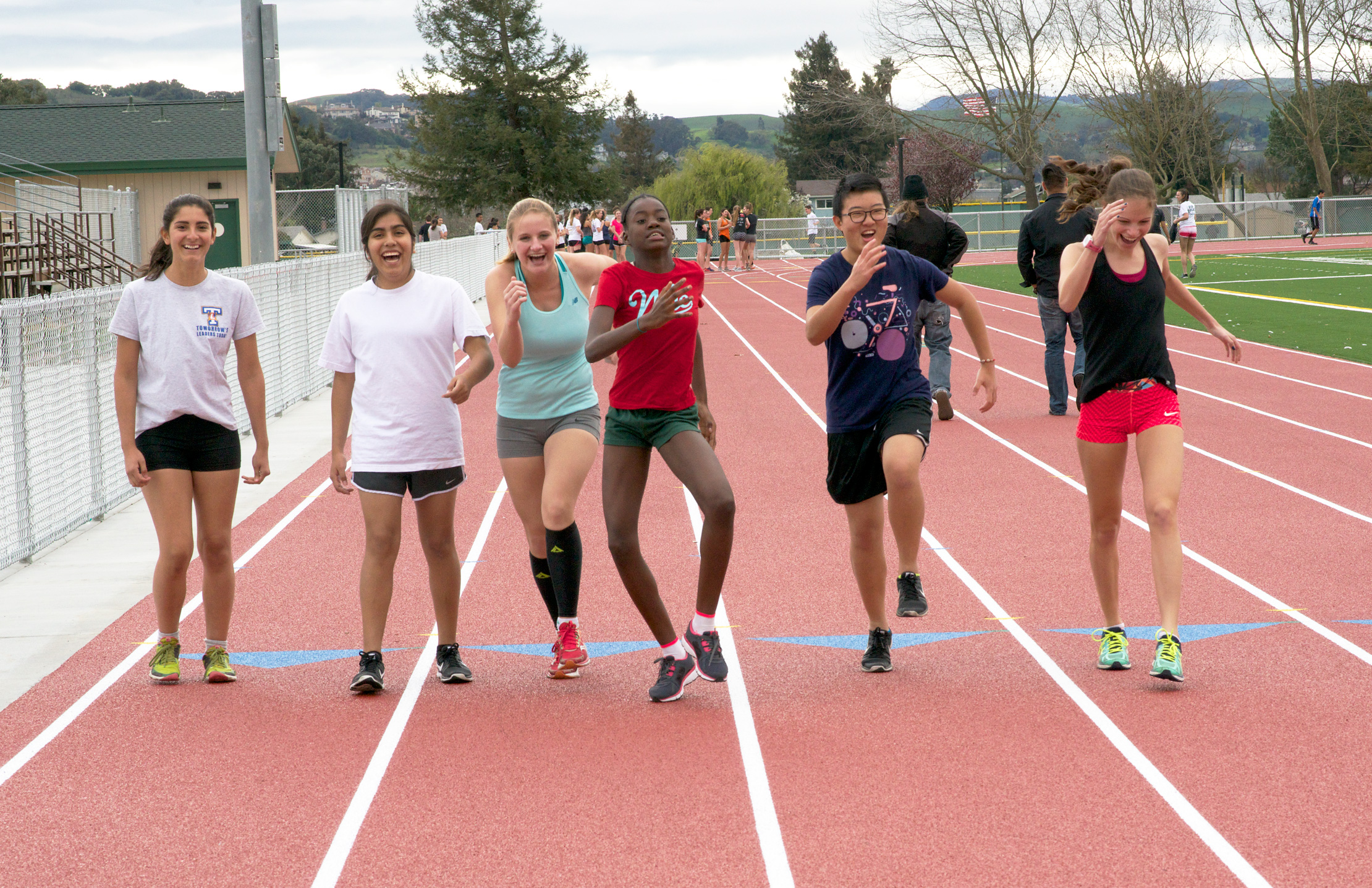 Athlete prepares for pole vault on a track with others watching.