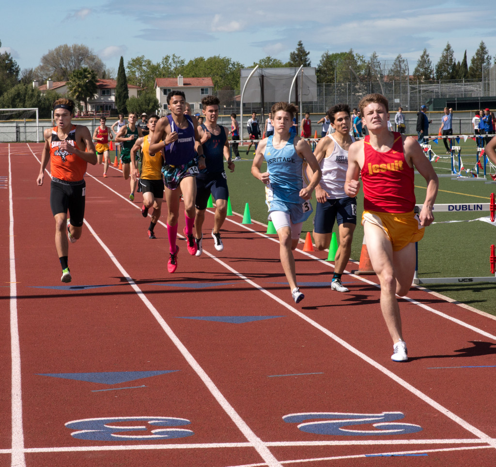 Athlete prepares for pole vault on a track with others watching.