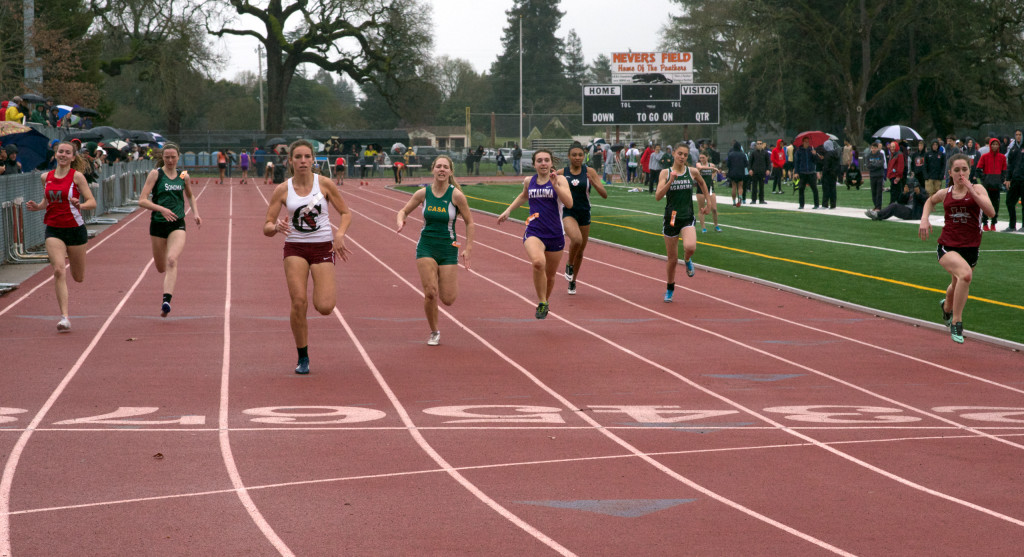 Athlete prepares for pole vault on a track with others watching.