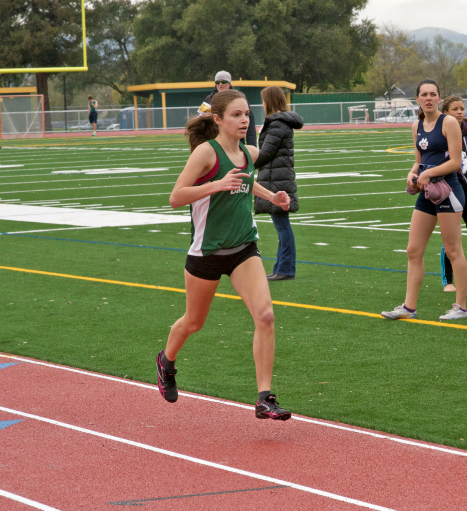 Athlete prepares for pole vault on a track with others watching.