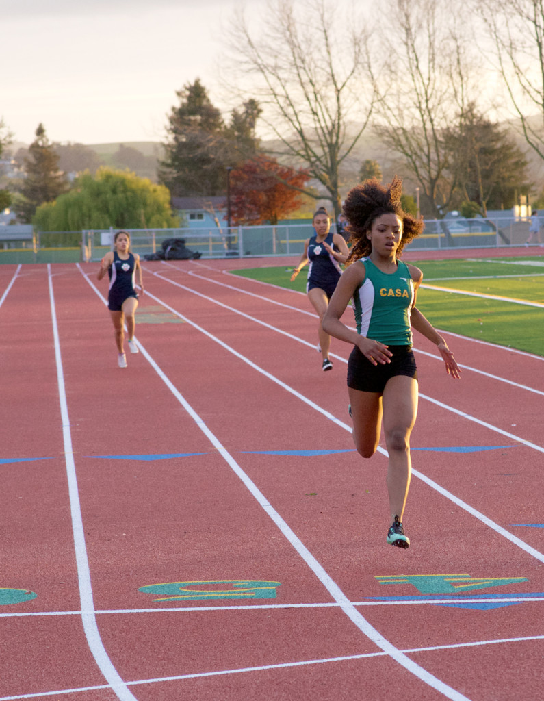 Athlete prepares for pole vault on a track with others watching.