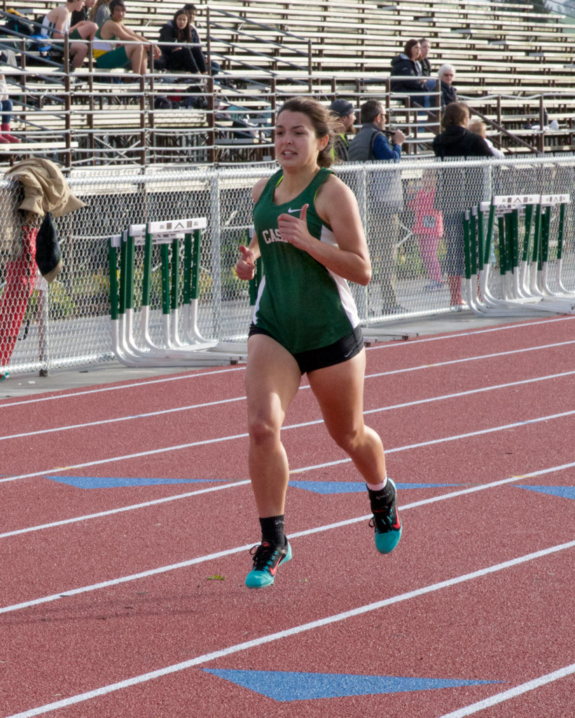 Athlete prepares for pole vault on a track with others watching.