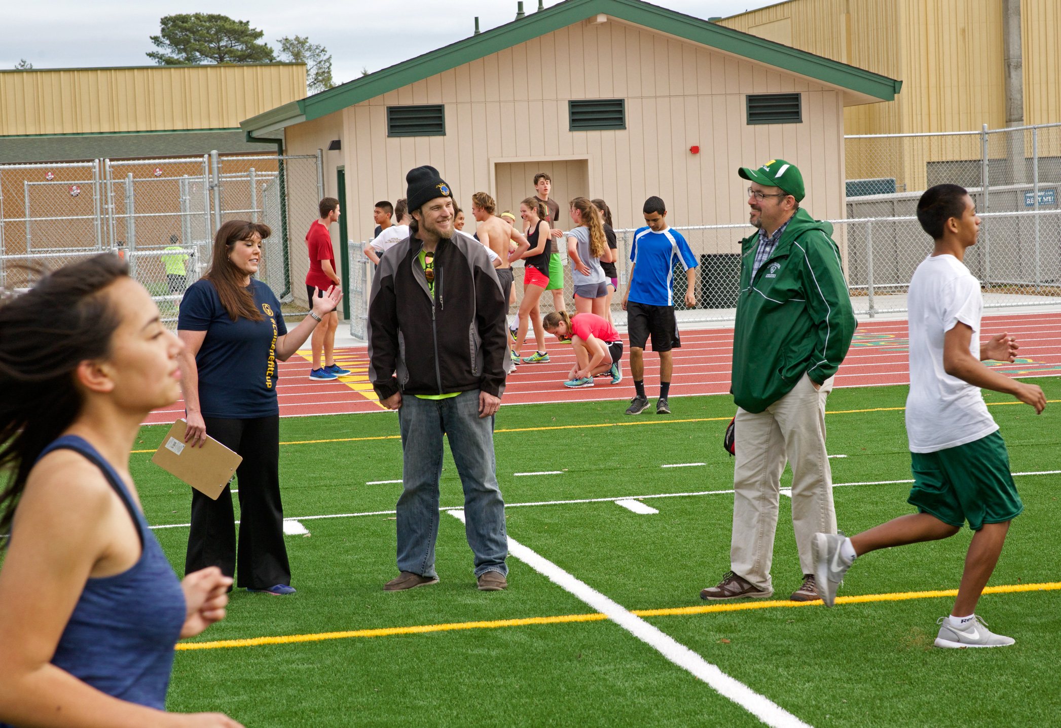 Athlete prepares for pole vault on a track with others watching.