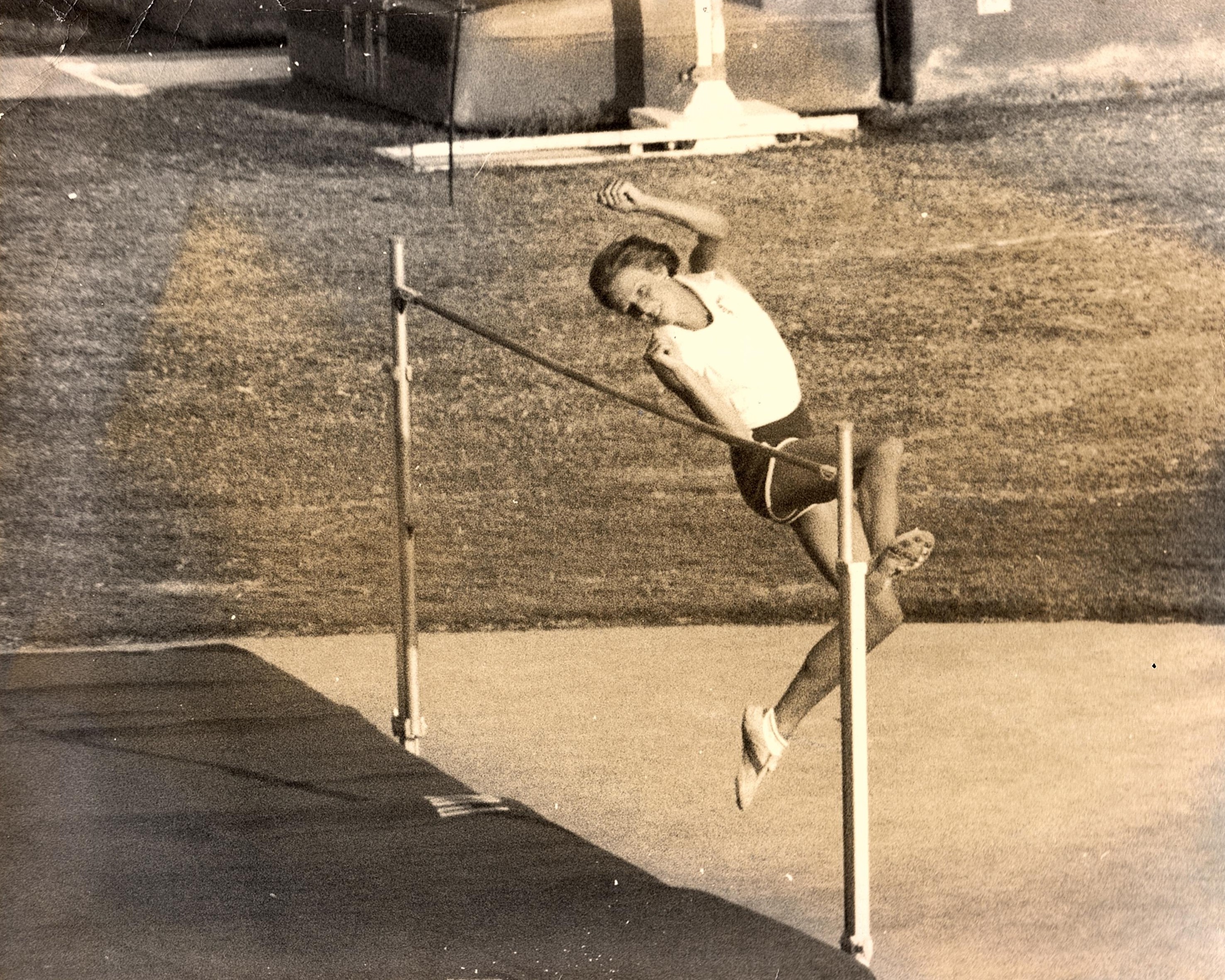 Athlete prepares for pole vault on a track with others watching.