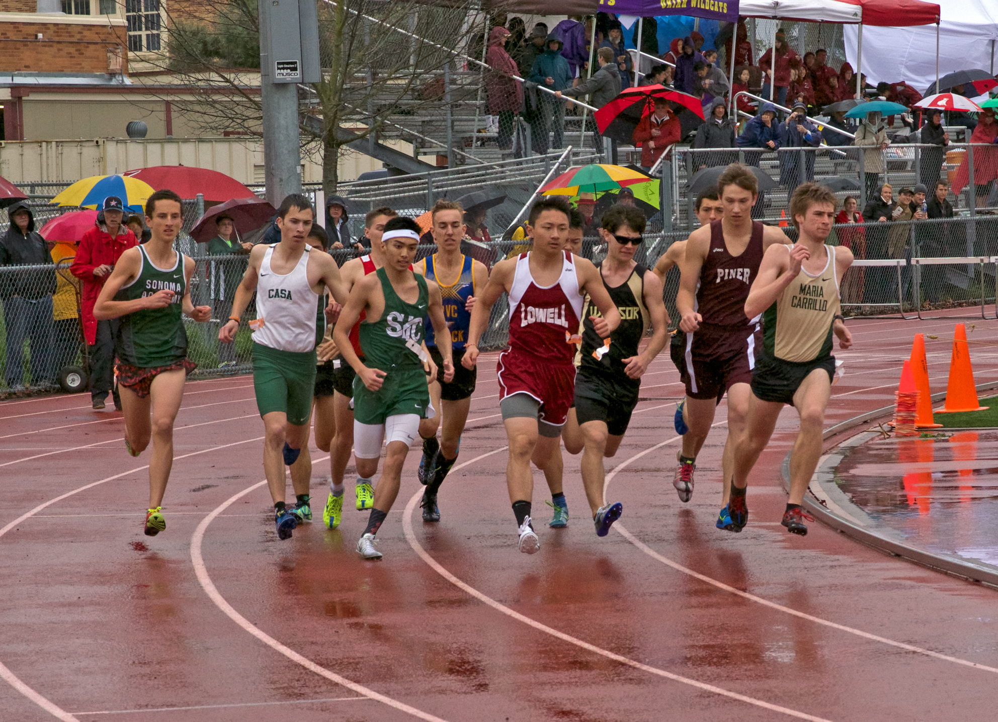 Athlete prepares for pole vault on a track with others watching.