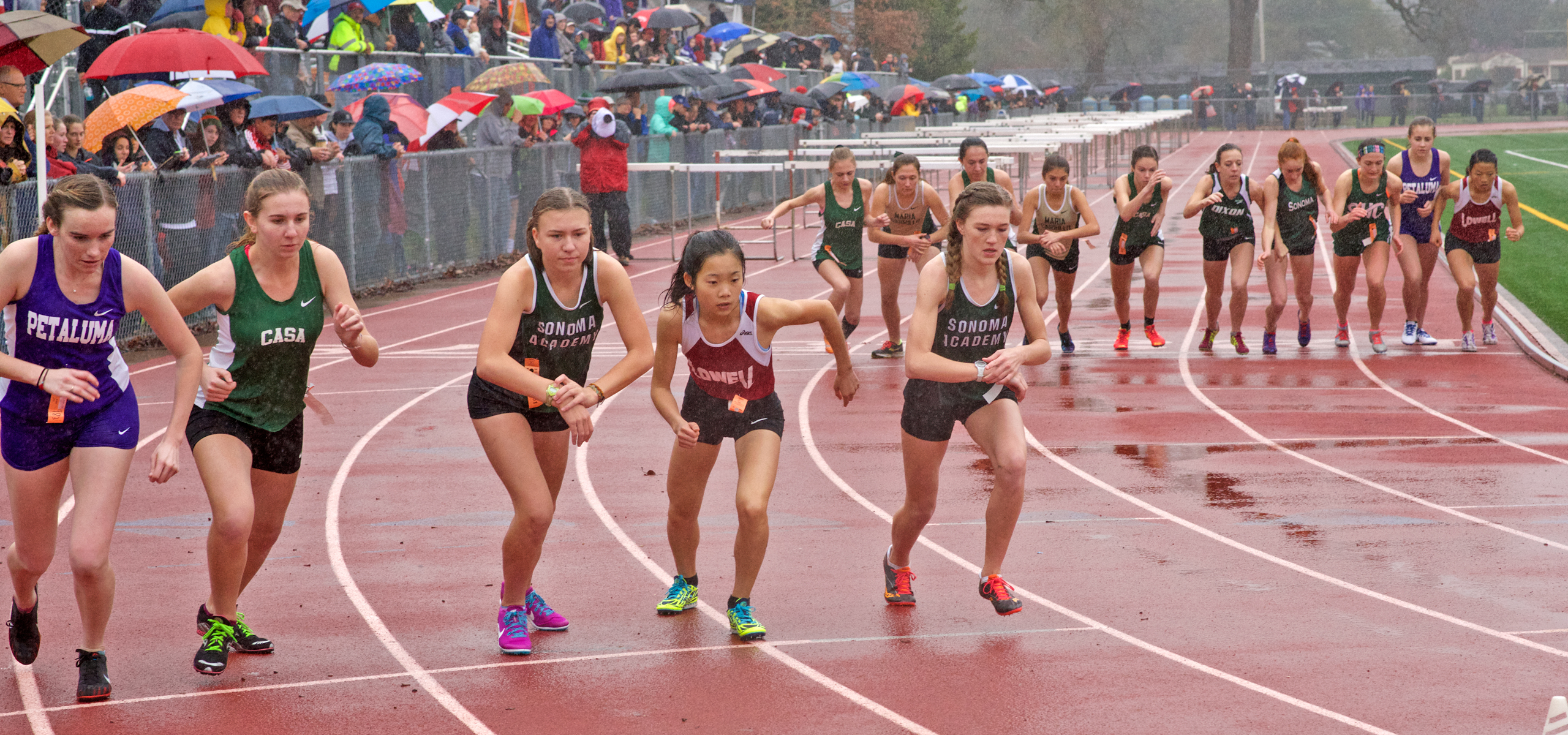 Athlete prepares for pole vault on a track with others watching.