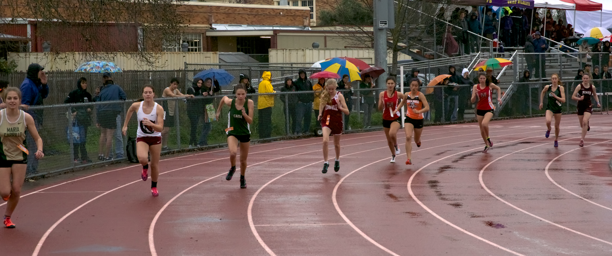 Athlete prepares for pole vault on a track with others watching.