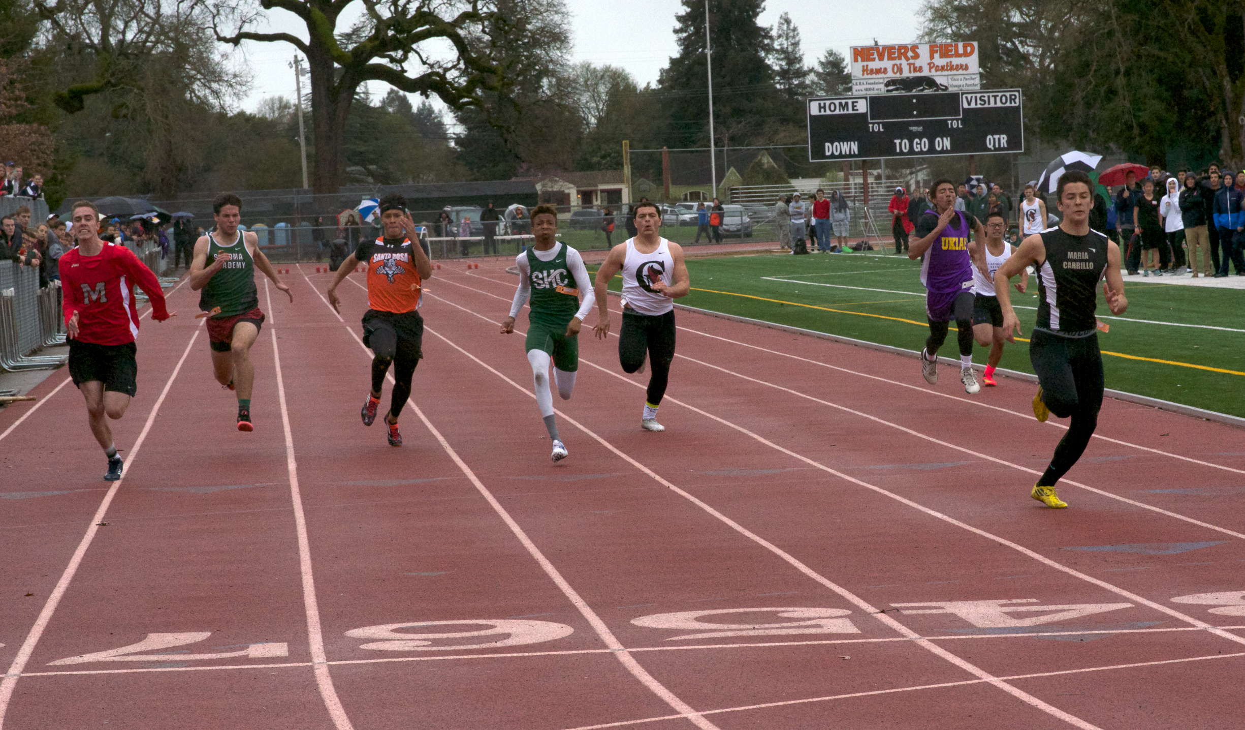 Athlete prepares for pole vault on a track with others watching.