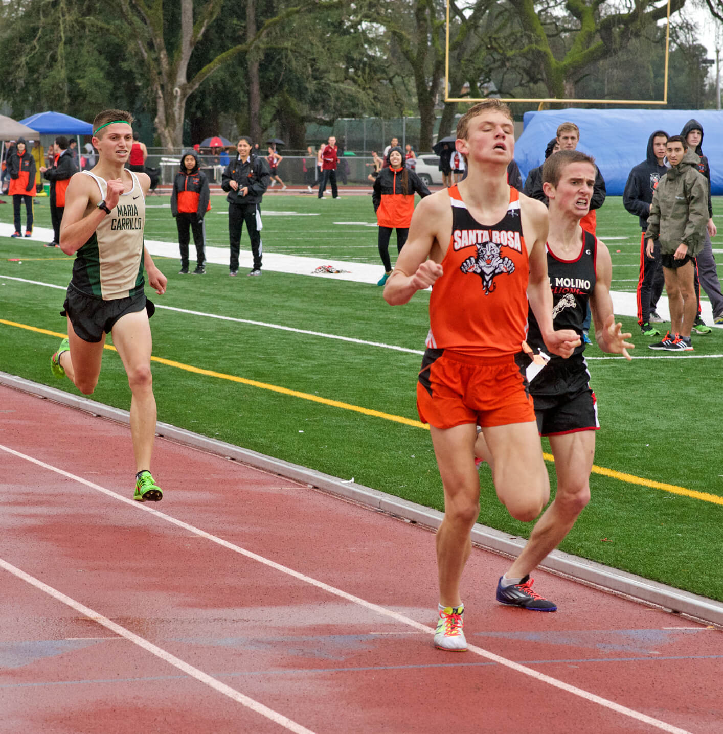 Athlete prepares for pole vault on a track with others watching.