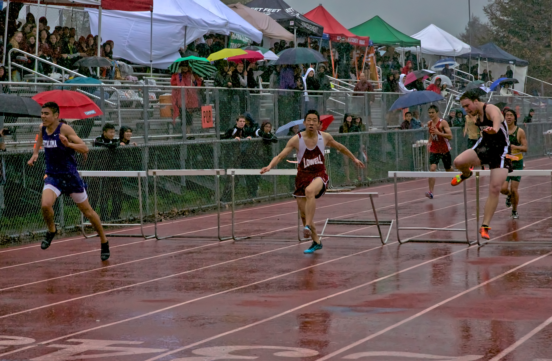 Athlete prepares for pole vault on a track with others watching.