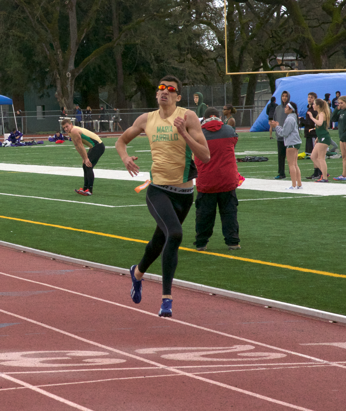 Athlete prepares for pole vault on a track with others watching.