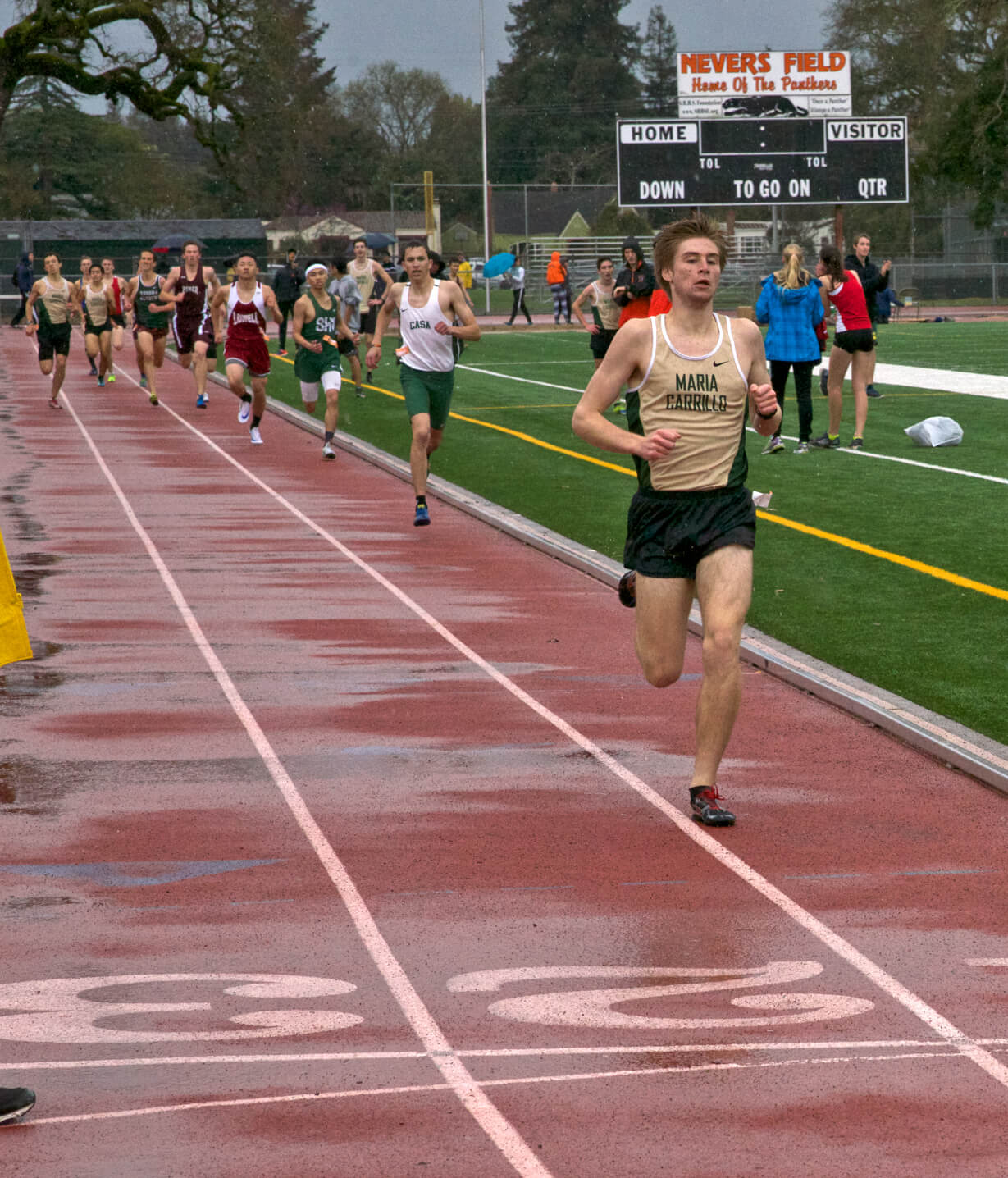 Athlete prepares for pole vault on a track with others watching.