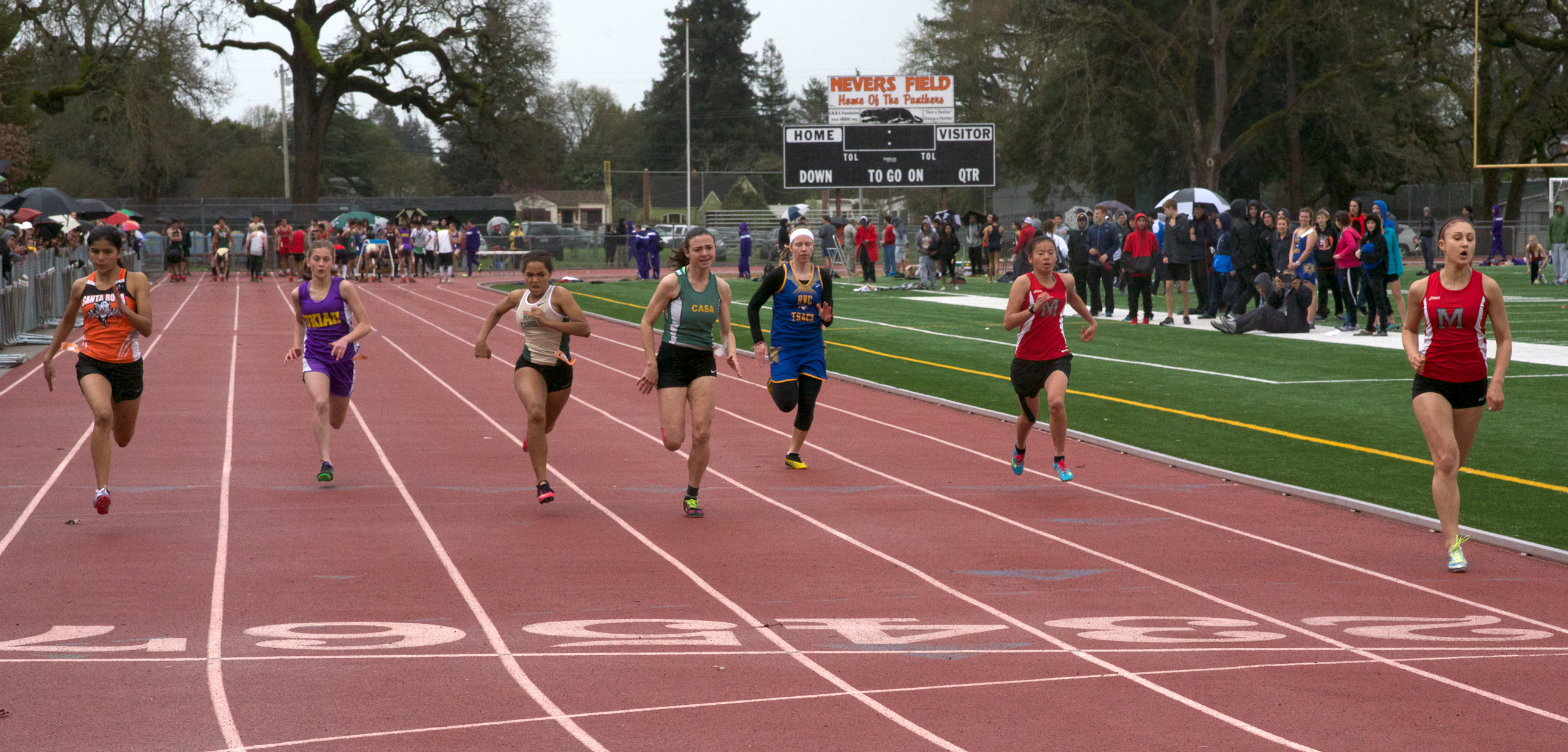Athlete prepares for pole vault on a track with others watching.