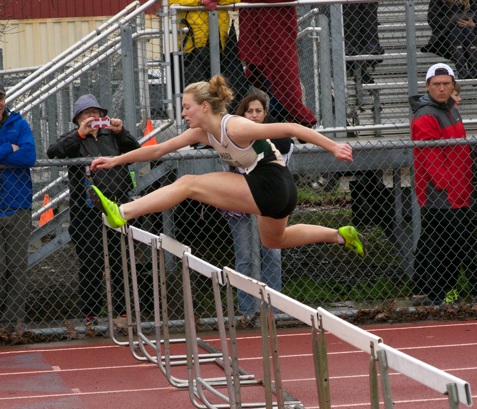 Athlete prepares for pole vault on a track with others watching.