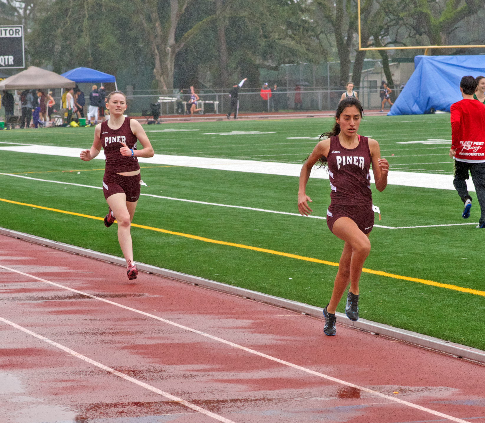 Athlete prepares for pole vault on a track with others watching.
