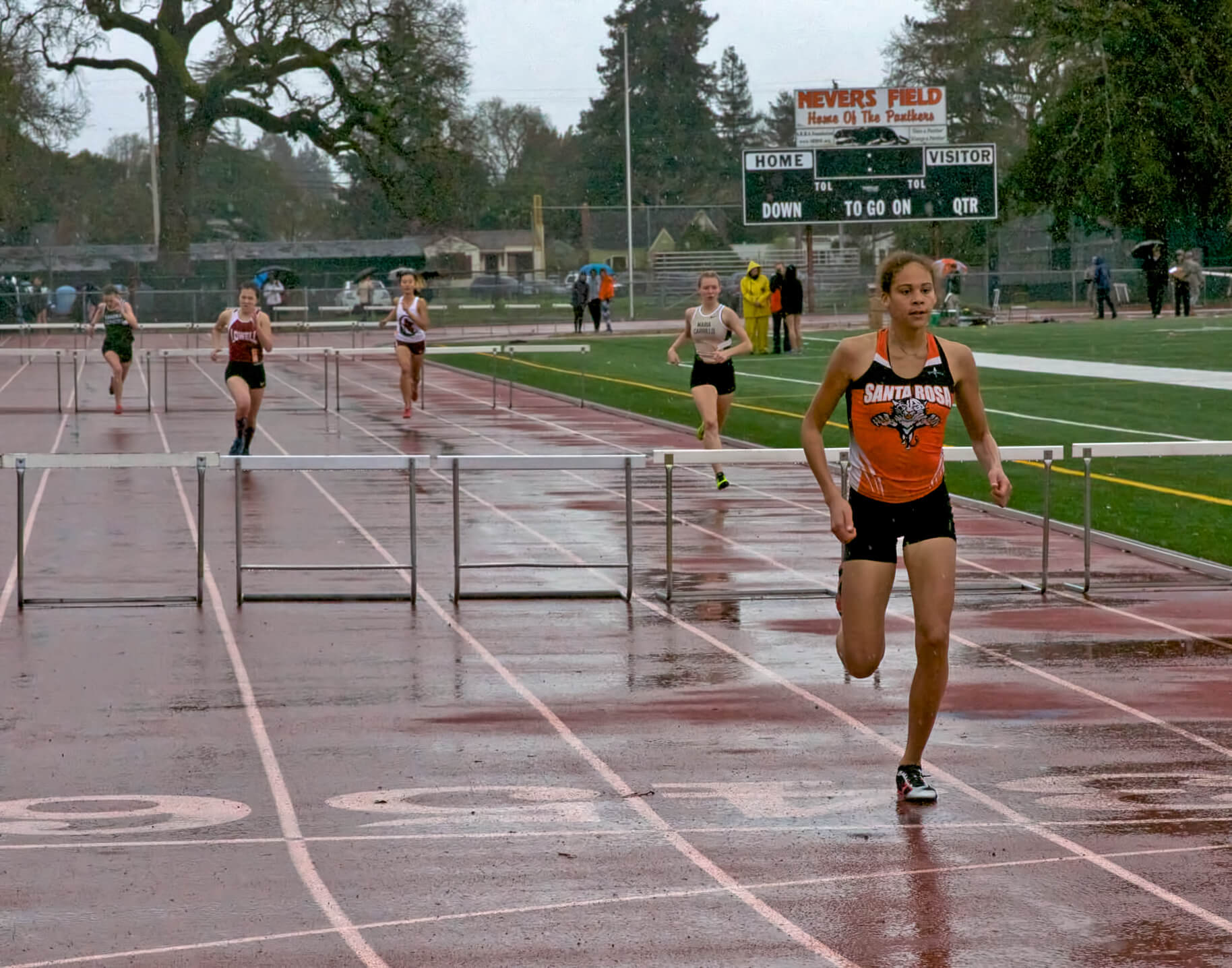 Athlete prepares for pole vault on a track with others watching.
