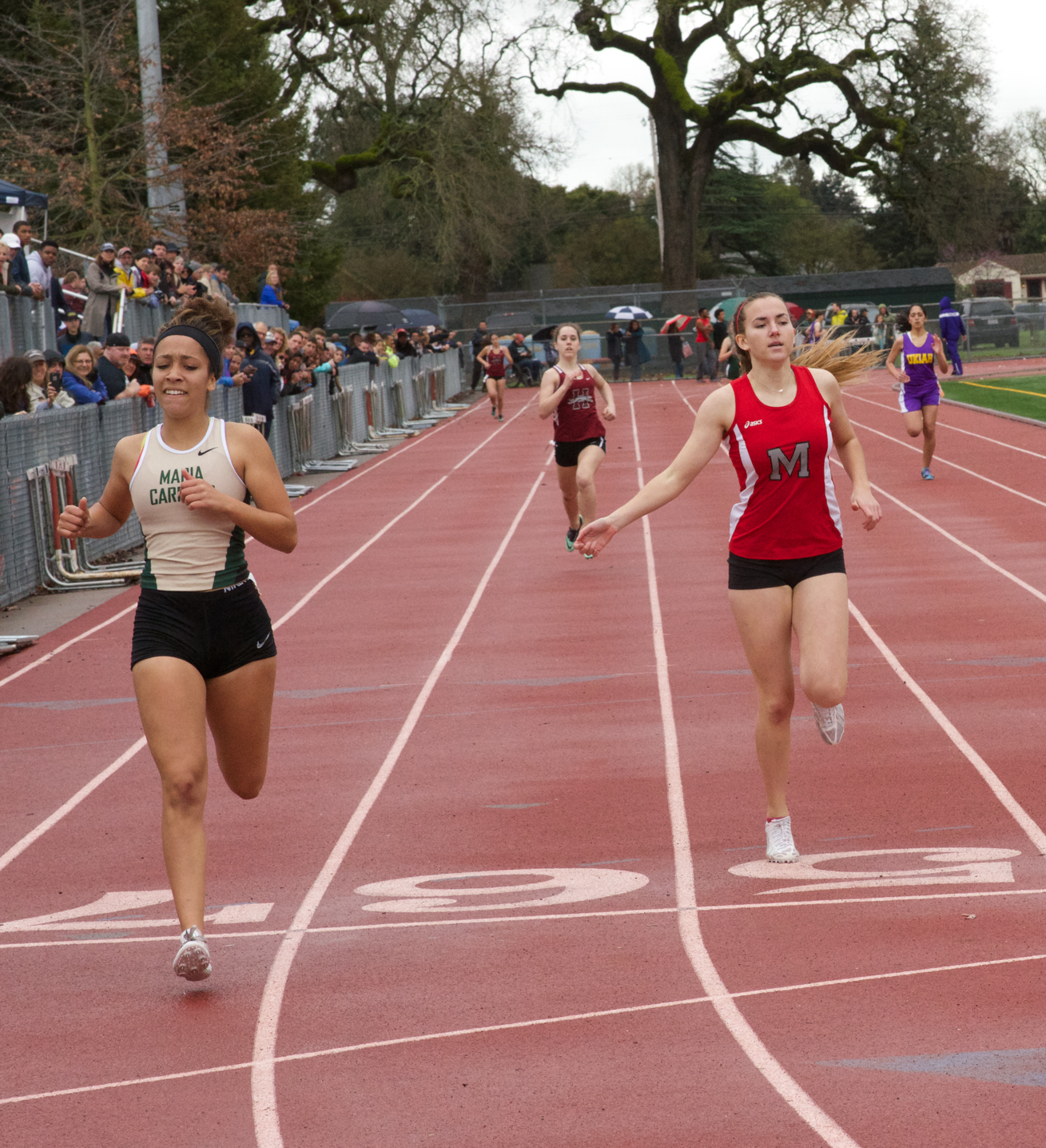 Athlete prepares for pole vault on a track with others watching.