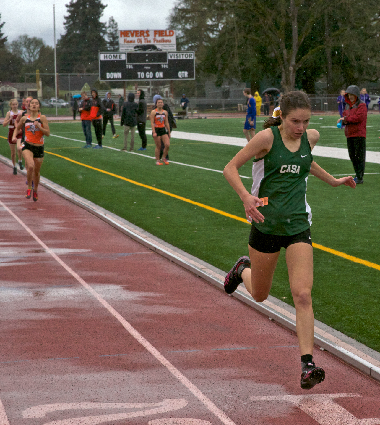 Athlete prepares for pole vault on a track with others watching.