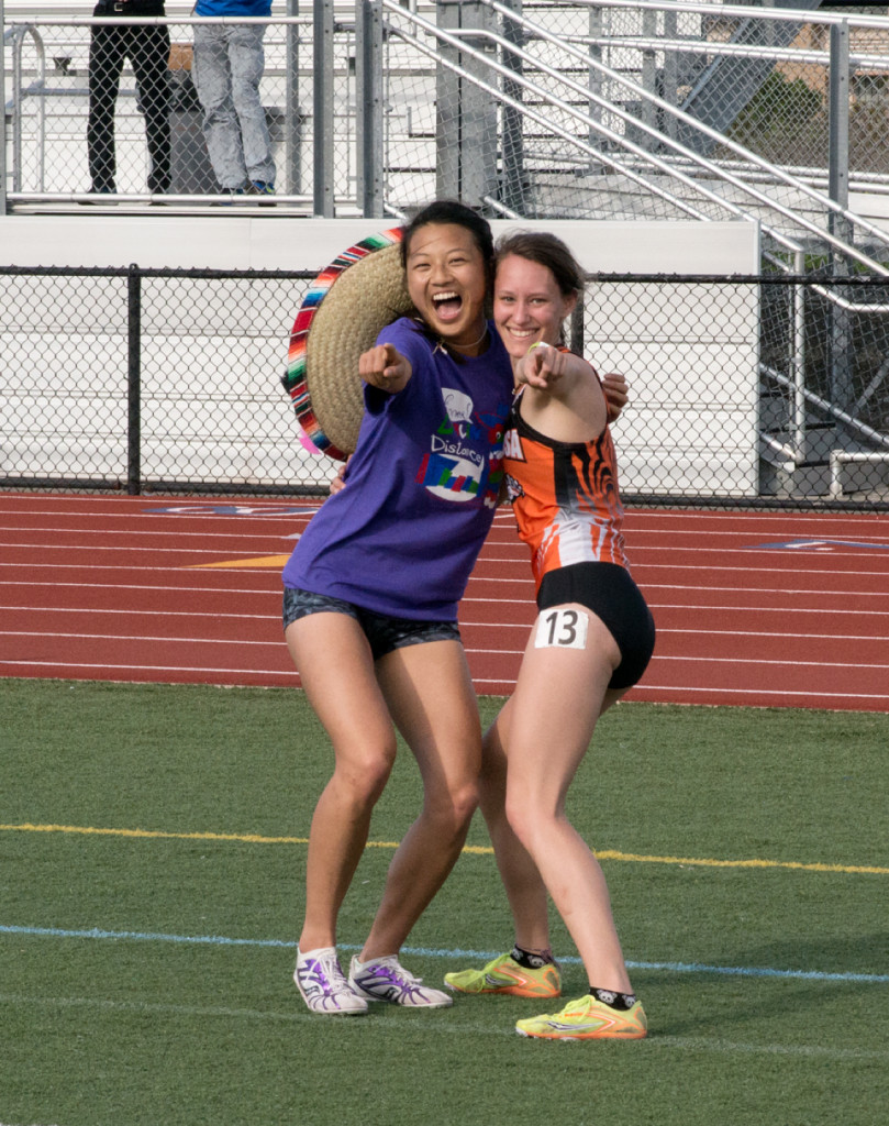 Athlete prepares for pole vault on a track with others watching.