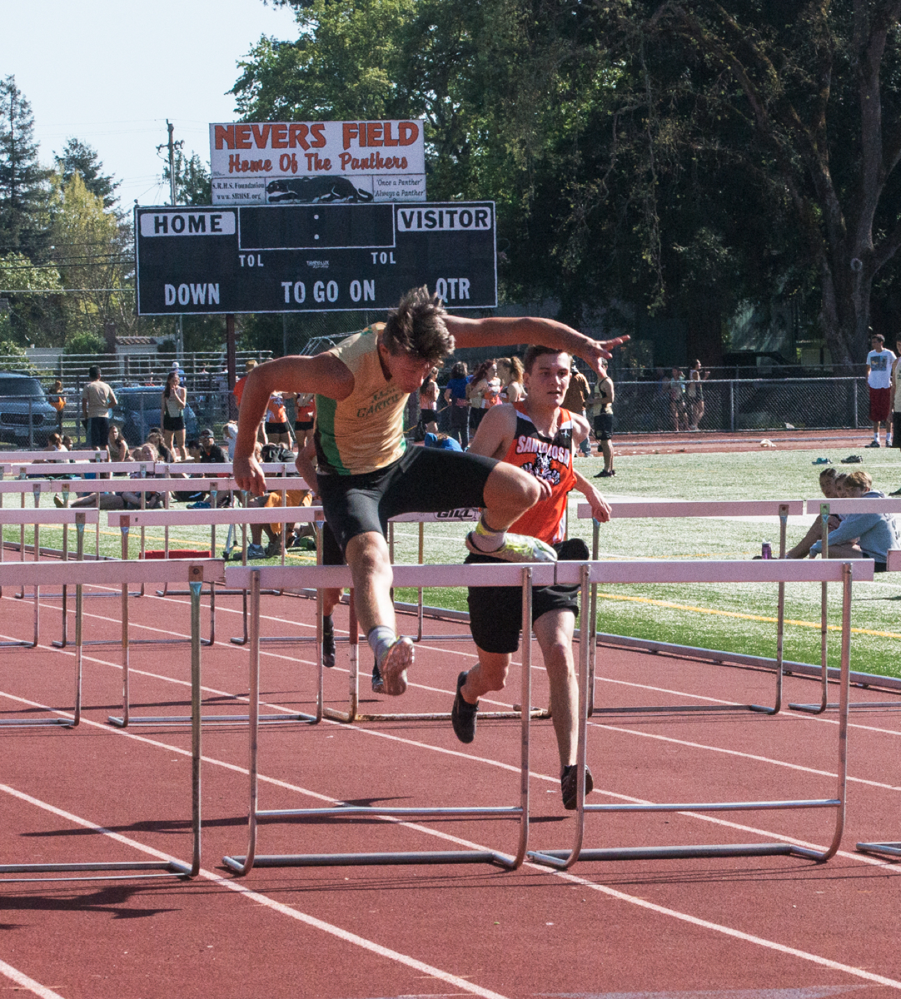 Athlete prepares for pole vault on a track with others watching.