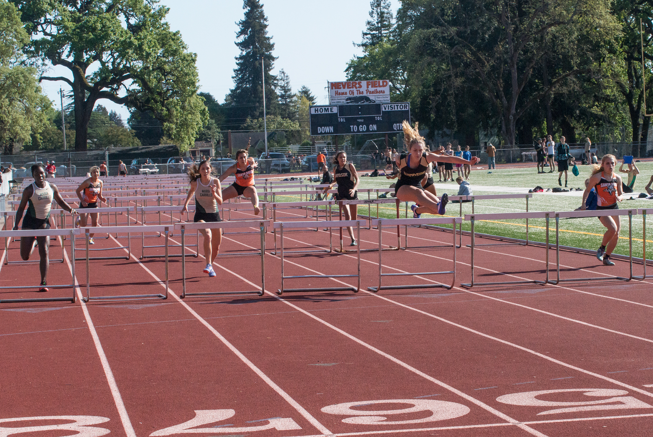 Athlete prepares for pole vault on a track with others watching.