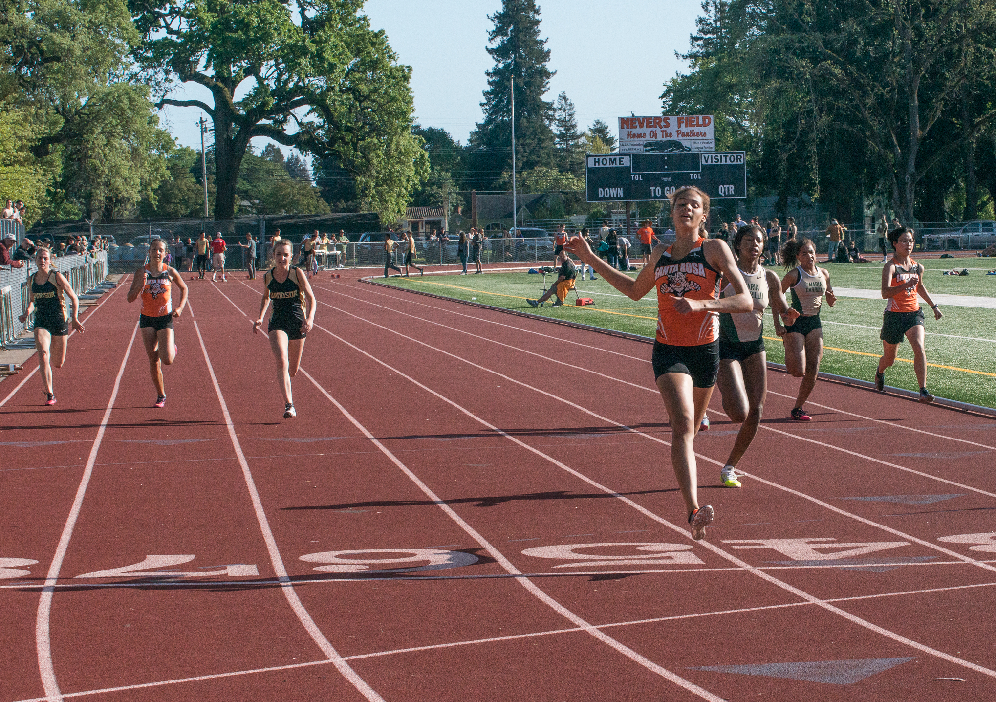 Athlete prepares for pole vault on a track with others watching.
