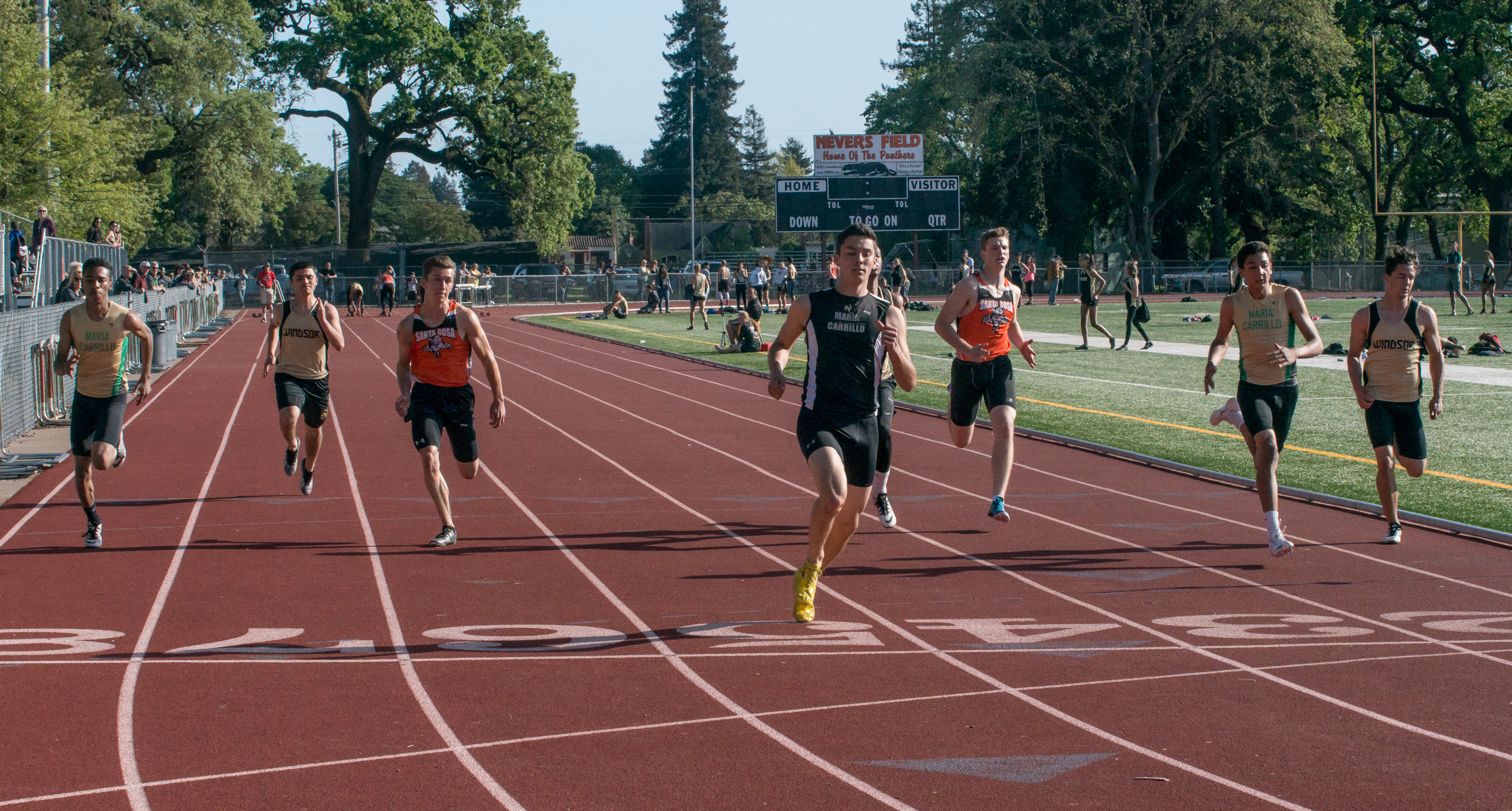Athlete prepares for pole vault on a track with others watching.