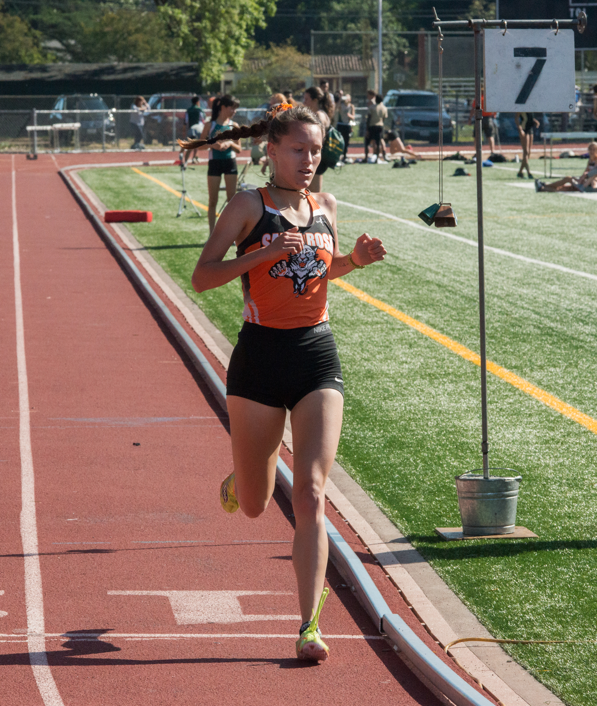 Athlete prepares for pole vault on a track with others watching.