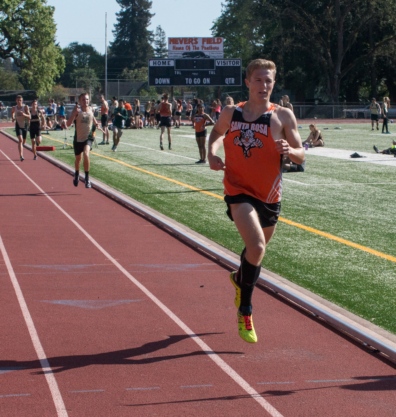 Athlete prepares for pole vault on a track with others watching.
