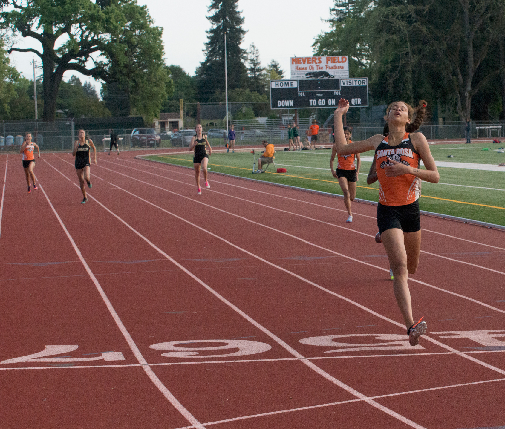 Athlete prepares for pole vault on a track with others watching.