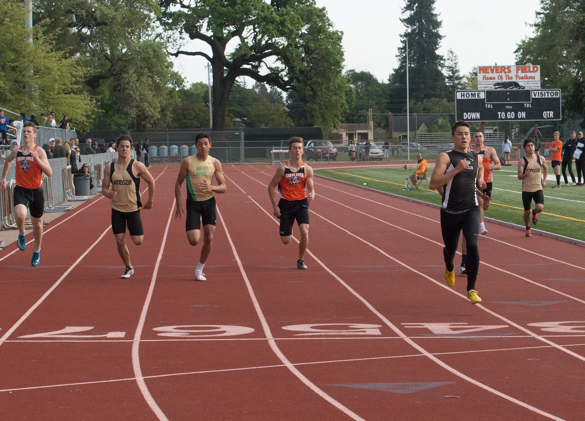 Athlete prepares for pole vault on a track with others watching.