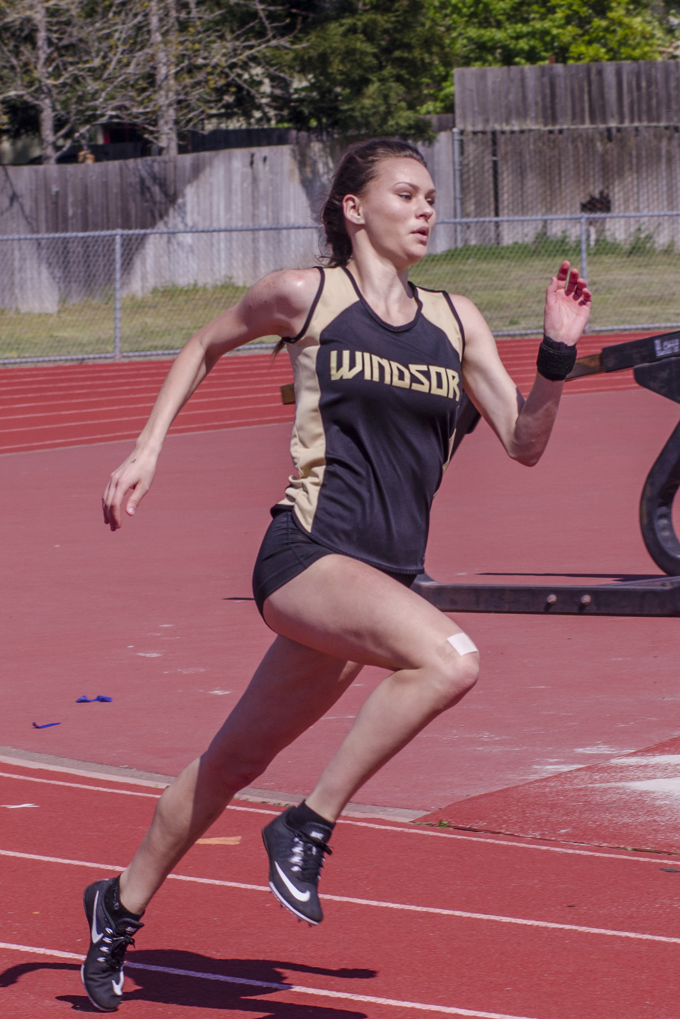 Athlete prepares for pole vault on a track with others watching.