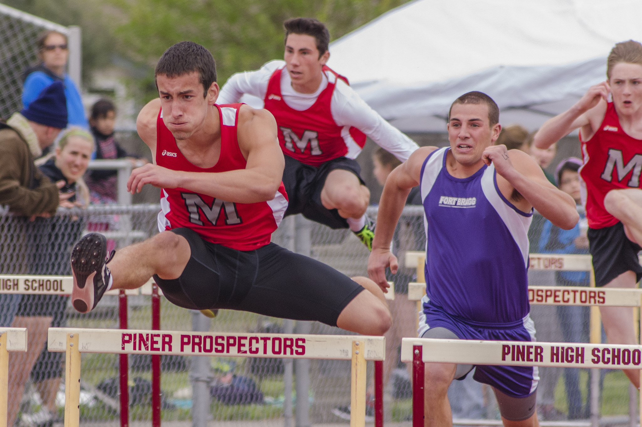 Athlete prepares for pole vault on a track with others watching.
