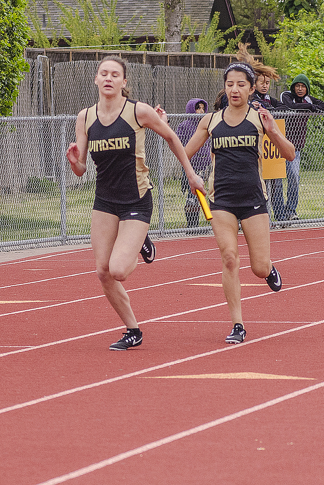 Athlete prepares for pole vault on a track with others watching.